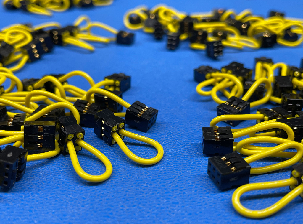At least 20 small yellow cable assemblies laid out on a table